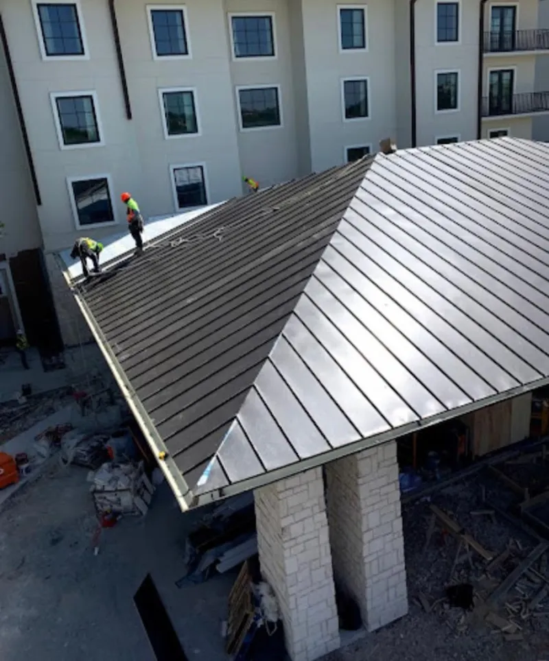 Crew installing standing seam metal roof panels on a commercial project in Lincoln Village